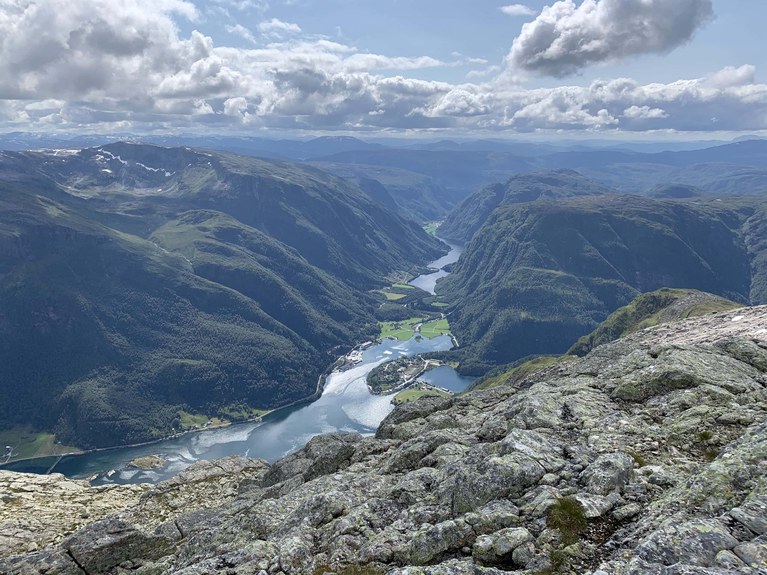 Kveldsutsikt over Hyen med snødekte fjell, fjorden og ein opplyst idrettsplass